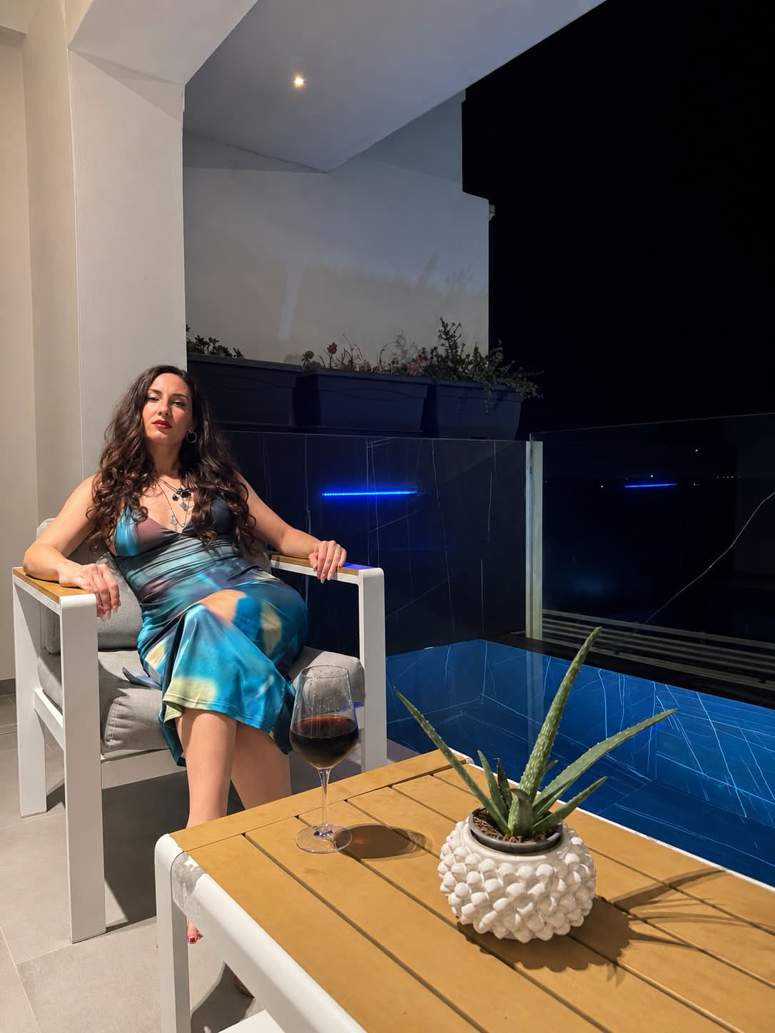 Samantha seduta a bordo piscina durante una serata